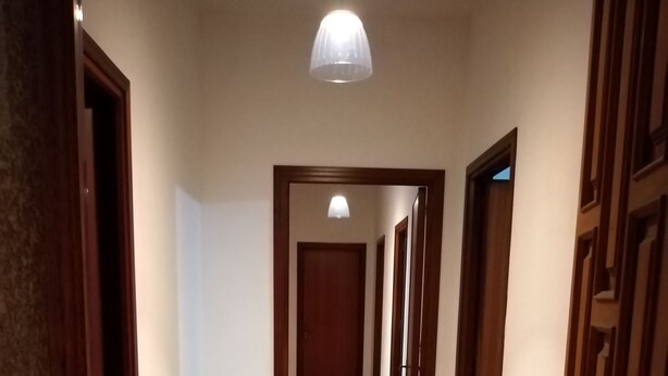 Un pasillo con suelo de baldosas, puertas de madera y una lámpara en el techo.