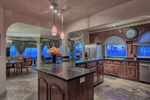 A spacious kitchen with a large island, wooden cabinets, and a clock on the wall.
