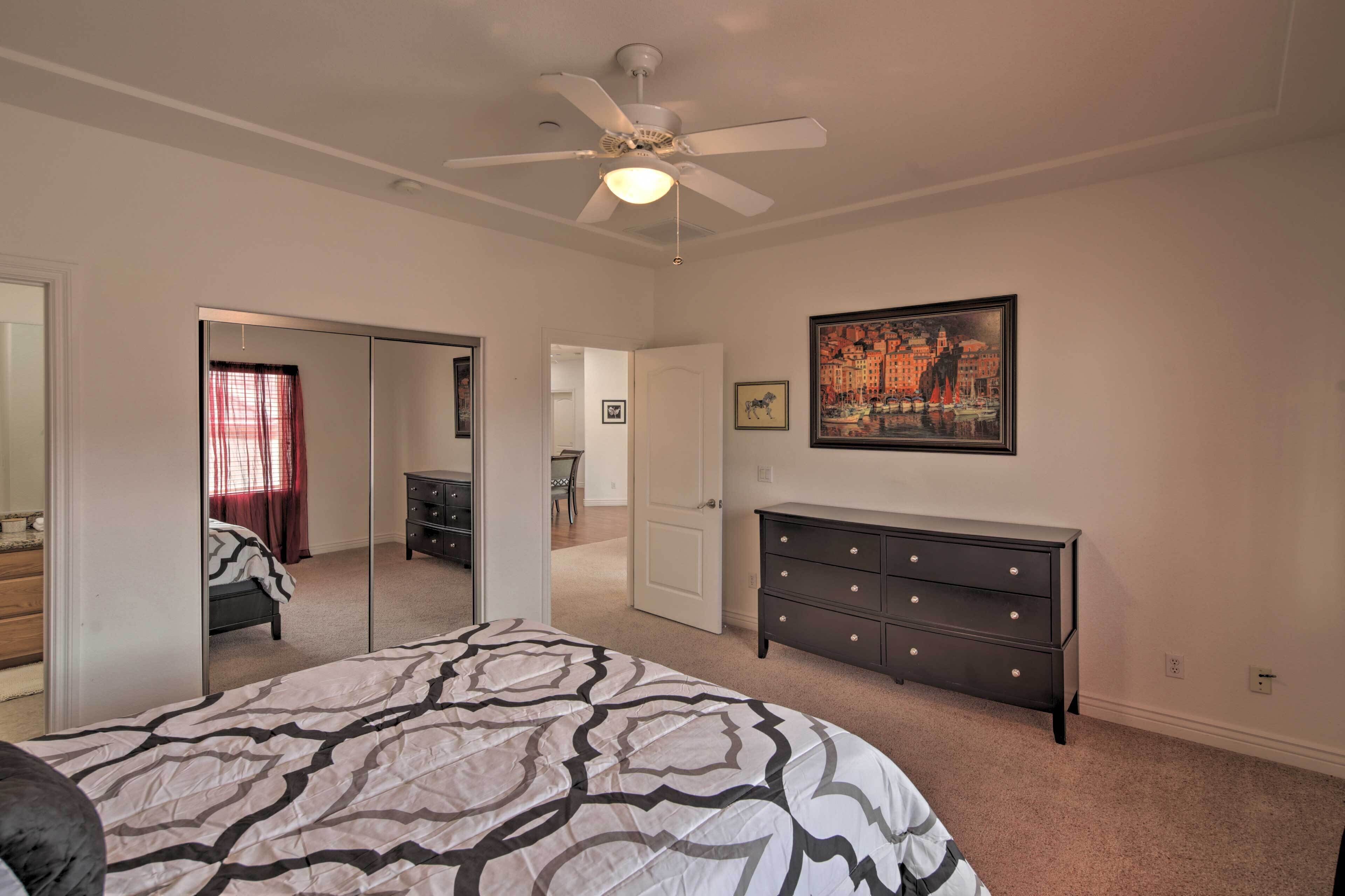 A bedroom with a bed, dresser, and a ceiling fan.