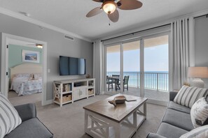A spacious living room with a large sliding glass door leading to a balcony with a view of the ocean. - Twin Palms 1002 by Best Beach Getaways (Panama City Beach)