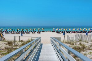A beach with a wooden walkway leading to the shore, rows of beach chairs, and umbrellas. - Twin Palms 1002 by Best Beach Getaways (Panama City Beach)