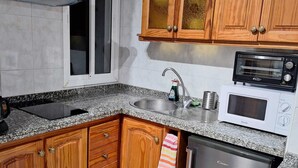 A kitchen with wooden cabinets, a built-in oven, a microwave, and a dishwasher. - Las Galletas 2A, sun, beach, relaxation (Las Galletas)