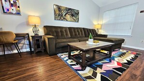 Un salon avec un canapé marron, une table basse en bois, un tapis à motifs et deux lampes.