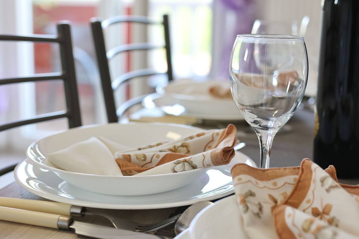 A dining table set with plates, a wine glass, and a napkin.
