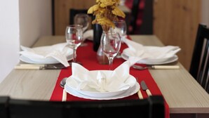 A dining table set with white plates, silverware, and a red table runner. - Apartments Saphron Beach (Pasman)