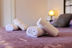 A neatly made bed with rolled white towels and a pillow on a patterned bedspread. - Apartments Saphron Beach (Pasman)
