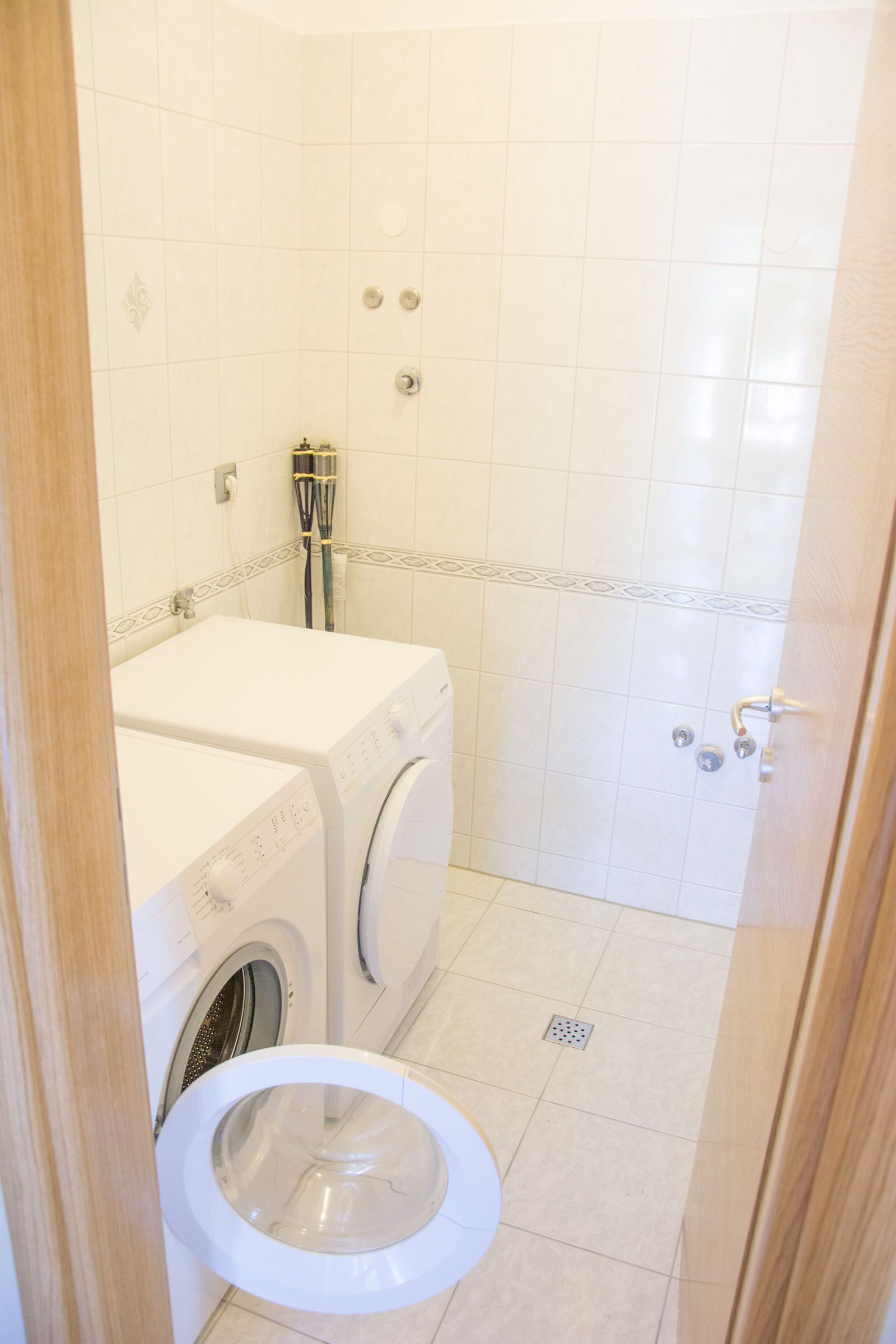 Et lille badeværelse med toilet, vaskemaskine og bruser.