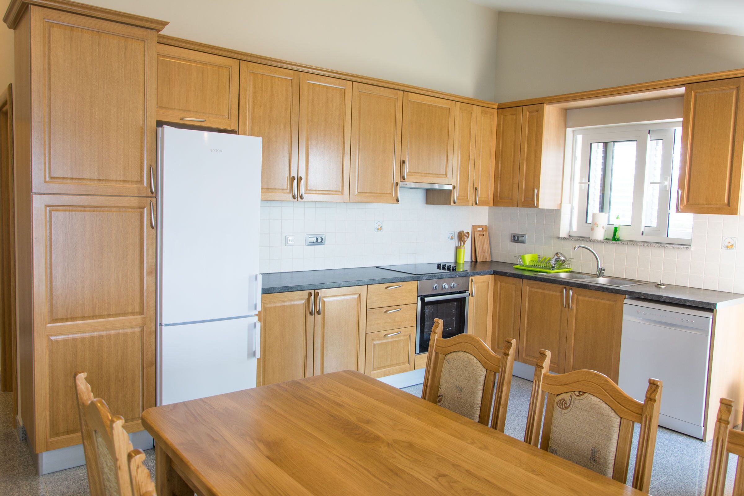 Una cocina con armarios de madera, un refrigerador, una estufa y un lavavajillas.
