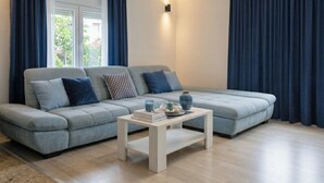 A modern living room with a grey sofa, a white coffee table, and blue curtains. - Apartment Svabo (Dolac)