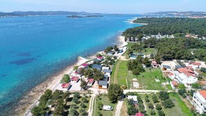 Une vue aérienne d’une zone côtière avec des maisons, une plage et une mer bleue et limpide.