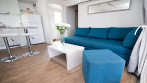 Un salon moderne avec un canapé bleu, une table basse blanche et un vase rempli de fleurs blanches.