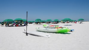 A beach with kayaks, umbrellas, and beach chairs. - Beach Cottage 120 at Hidden Dunes by Best Beach Getaways (Miramar Beach)