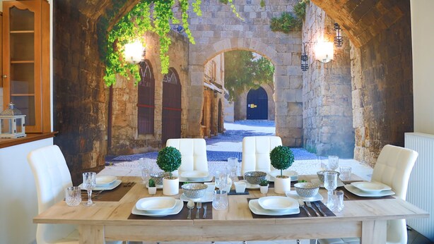 A dining table set in a room with stone arches and a view of a courtyard. - SeaSunrise: Modern, spacious Apt, A/C, WiFi, Near beach (Perama)