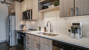 Una cocina moderna con electrodomésticos de acero inoxidable, armarios de madera, un lavamanos doble y una cafetera.