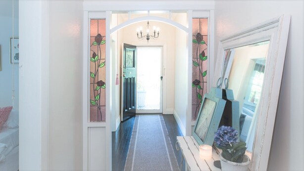 A hallway with a chandelier, a mirror, and a door with stained glass. - Casa Antica, 200m walk to Bowral Township, family friendly and strictly NO PETS! (Bowral)