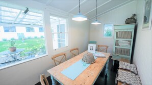 A dining area with a wooden table, chairs, and hanging pendant lights. There is a view of a garden through large windows. - Casa Antica, 200m walk to Bowral Township, family friendly and strictly NO PETS! (Bowral)