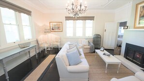 A spacious living room with a white sofa, armchairs, a coffee table, and a fireplace. - Casa Antica, 200m walk to Bowral Township, family friendly and strictly NO PETS! (Bowral)