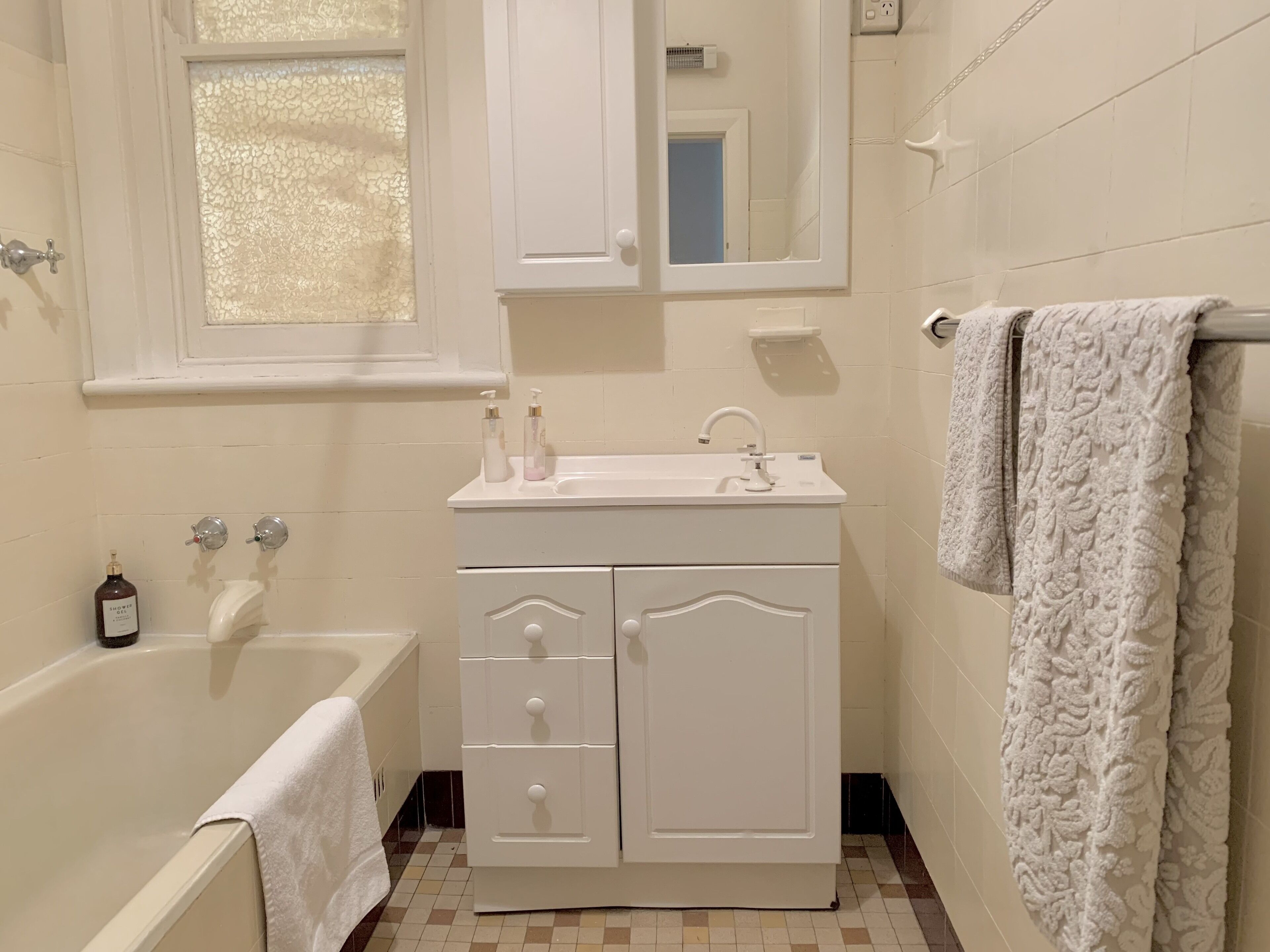 A bathroom with a bathtub, a sink with a mirror above it, and a towel rack with a towel.