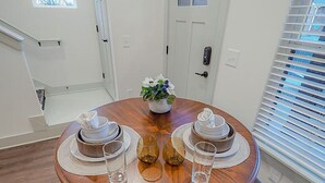 Un comedor con una mesa redonda de madera, dos sillas y una planta en maceta.