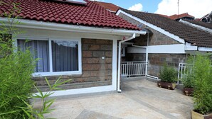 A residential house with a tiled roof, brick exterior, and a covered patio area with potted plants. - City of the Sun Newly renovated loving house (Nairobi)