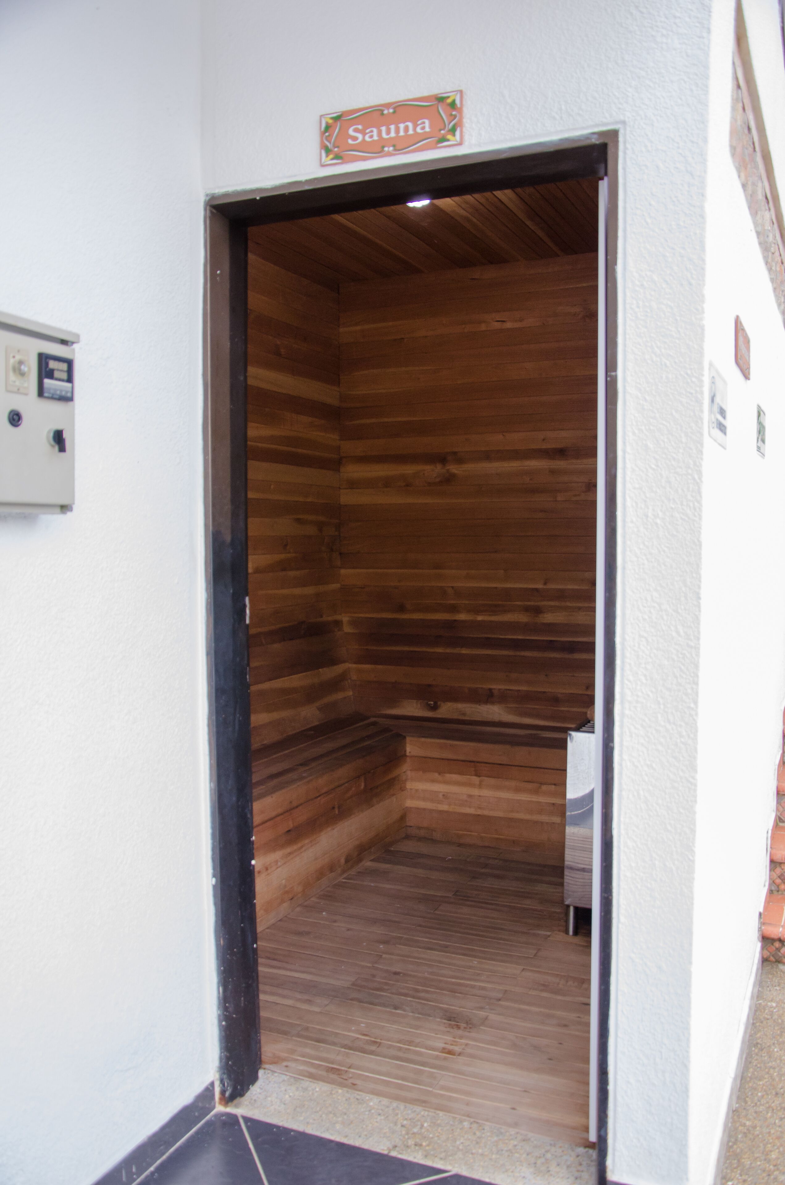 A sauna room with wooden walls and a sign above the door.