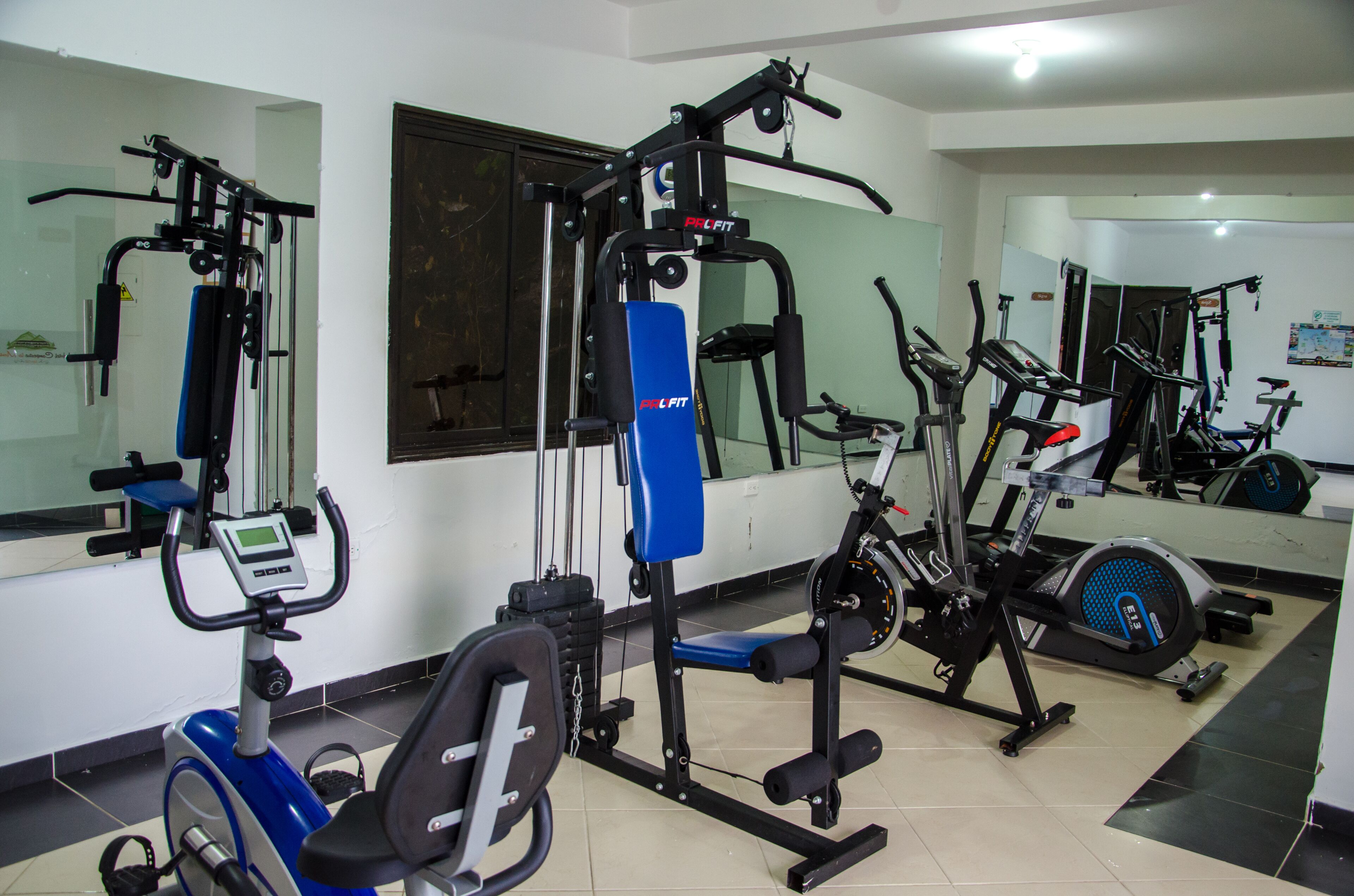 Un gimnasio con diverso equipo de ejercicio, que incluye una caminadora, una máquina elíptica y máquinas de pesas.