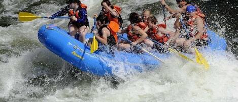 Un grupo de personas en una balsa inflable azul se desplaza por un río con rápidos.