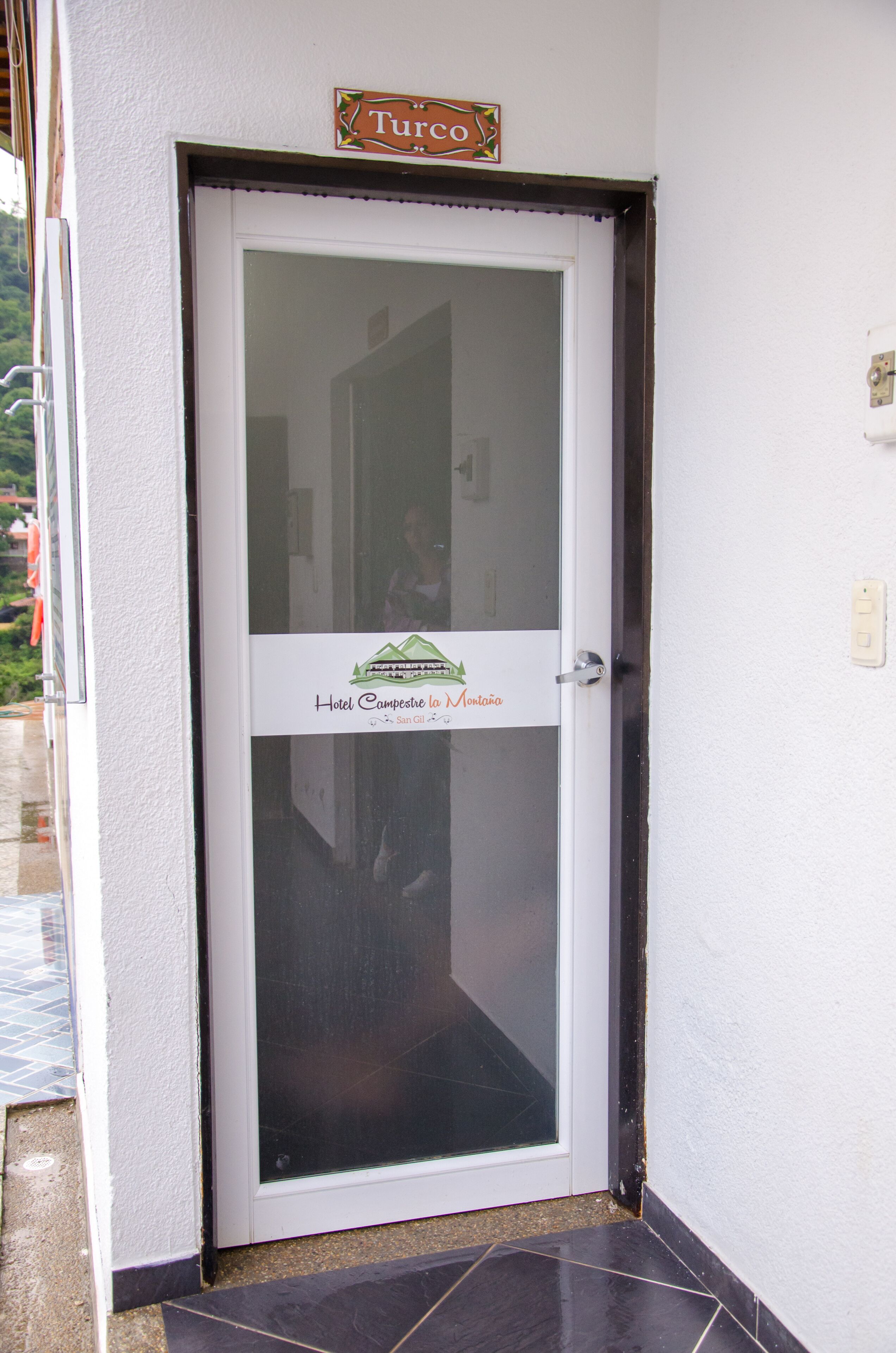A hotel entrance with a glass door, a sign above the door, and a logo on the door.