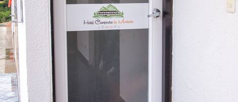 A hotel entrance with a glass door, a sign above the door, and a logo on the door.