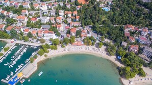 An aerial view of a coastal town with a marina, beach, and residential buildings. - Rooms Cico (Crikvenica)