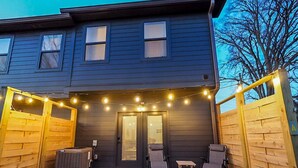 A two-story house with a dark exterior, a front door, and a small patio area with two chairs and a table. - *2bd/2.5bth | Near Downtown| Soccer Stadium* #D (Nashville)