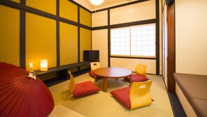 A traditional Japanese room with tatami flooring, a round table, and low yellow chairs. - Benifuji-ann (Kyoto)