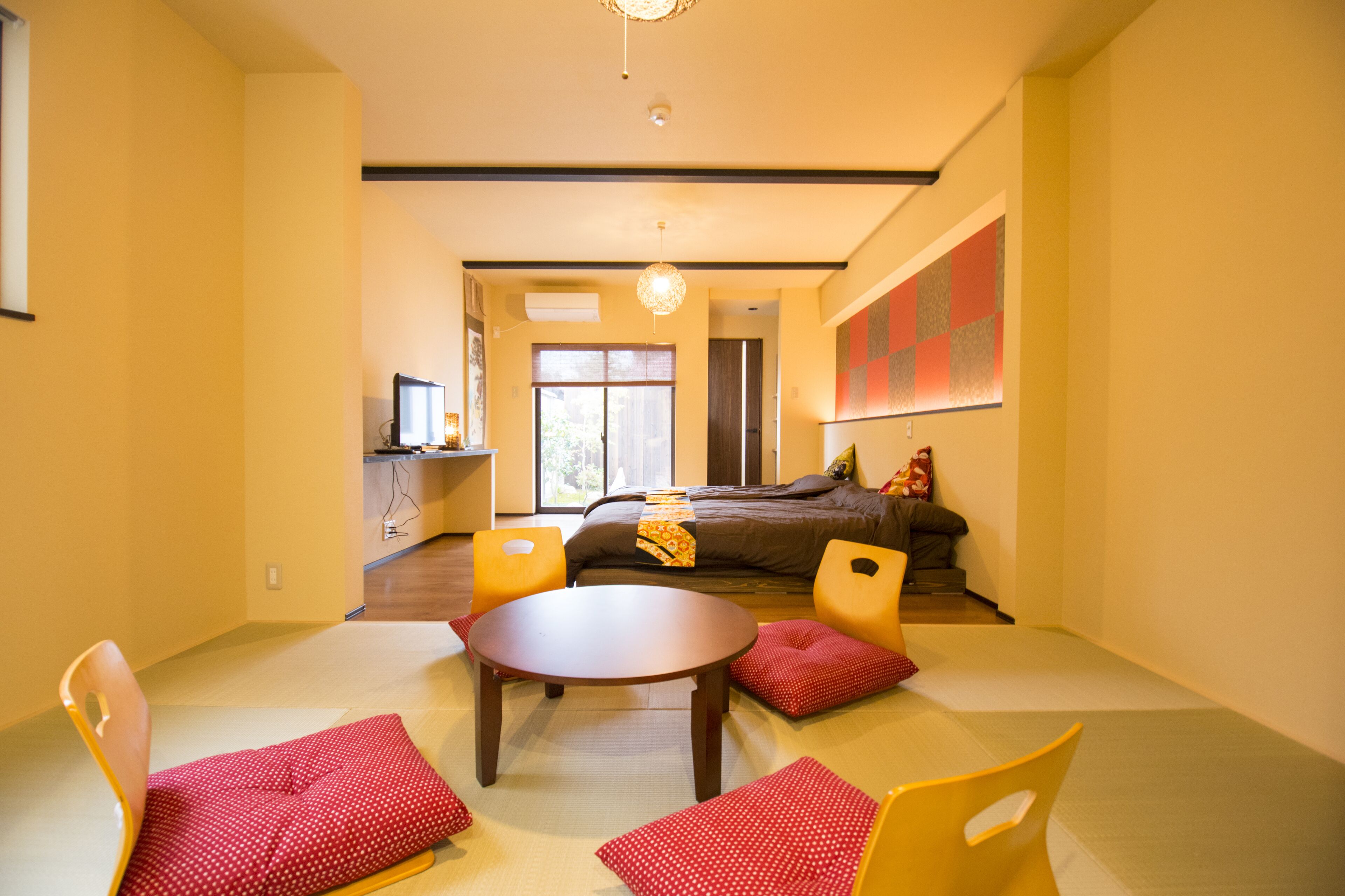 A modern room with a bed, two chairs, a table, and a TV.