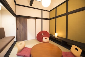 A traditional Japanese room with tatami flooring, a low table, and cushions.