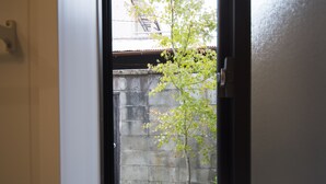 A view through a doorway into a courtyard with a tree, a stone wall, and a small rock. - Benifuji-ann (Kyoto)