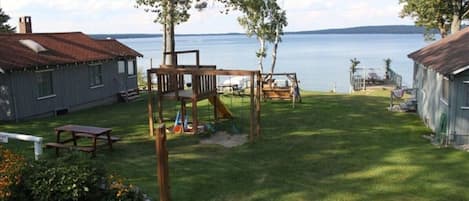 Un giardino con altalena in legno, tavolo da picnic e vista su un lago.