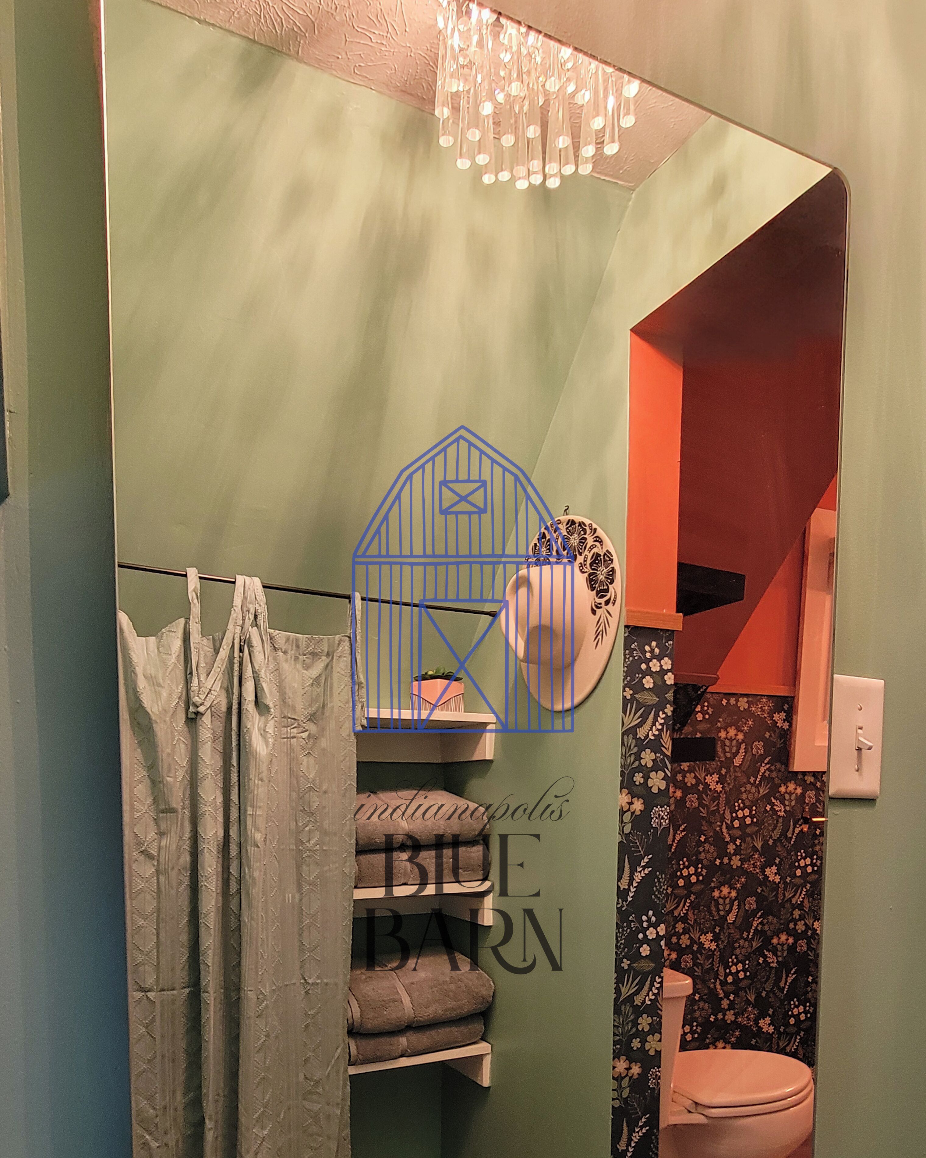 A bathroom with a shower curtain, a toilet, a towel rack, and a decorative birdhouse on a shelf.