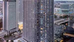 A high-rise building with a grid-like facade, surrounded by other modern buildings and a busy street below.