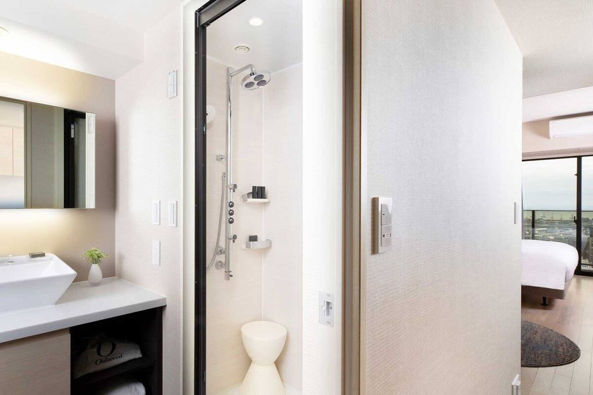 A modern bathroom with a large mirror, a sink, and a shower.