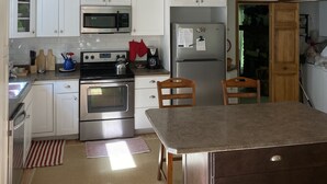 A modern kitchen with white cabinets, stainless steel appliances, and a wooden ceiling. - Entire Cottage with Additional Creek Cabin - Fallingwater Ohiopyle Seven Springs (Normalville)
