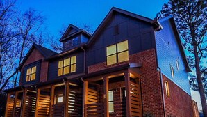 A two-story house with a covered porch, large windows, and a sloped roof.