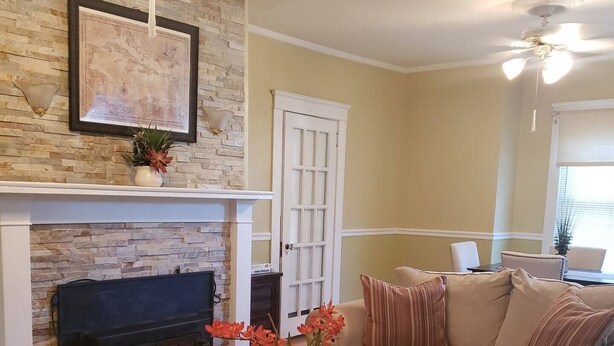 A living room with a fireplace, a sofa, a coffee table, and a ceiling fan.