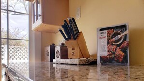A kitchen counter with a cookbook titled "Dinner in an Instant" by Melissa Clark, a knife block, and a small appliance.