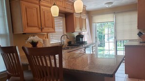 A kitchen with wooden cabinets, granite countertops, and pendant lighting.