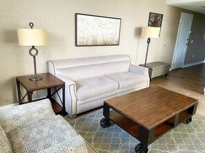 Ein Wohnzimmer mit einer Couch, einem Couchtisch, gemusterten Kissen und zwei Stehlampen.