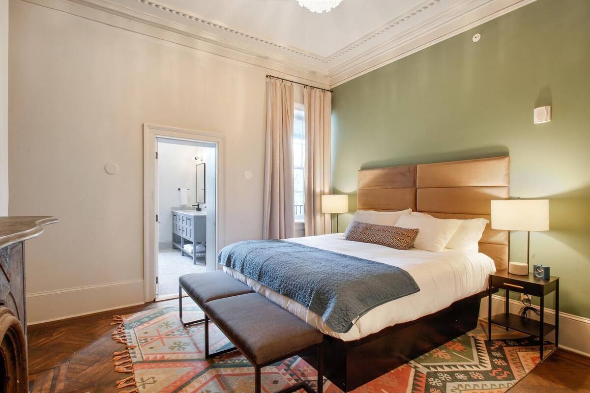 A bedroom with a large bed, a bench, a nightstand, and a dresser.