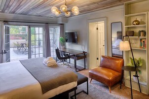 Une chambre d’hôtel avec un grand lit, un bureau, un fauteuil en cuir, une télévision et une bibliothèque.
