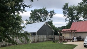 A backyard with a wooden fence, a hammock, and a patio area with outdoor furniture.