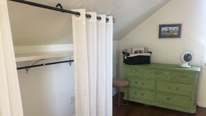 A room with a bunk bed, a green dresser, a fan, and a framed picture on the wall.