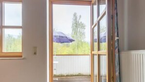 A room with a large sliding glass door leading to an outdoor deck, a window, and a radiator.